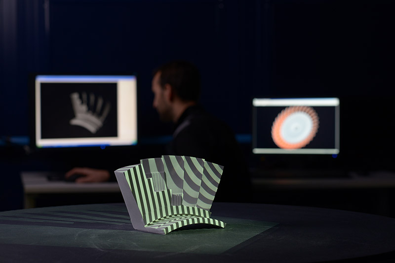 Production part and its digital twin on a screen in the background